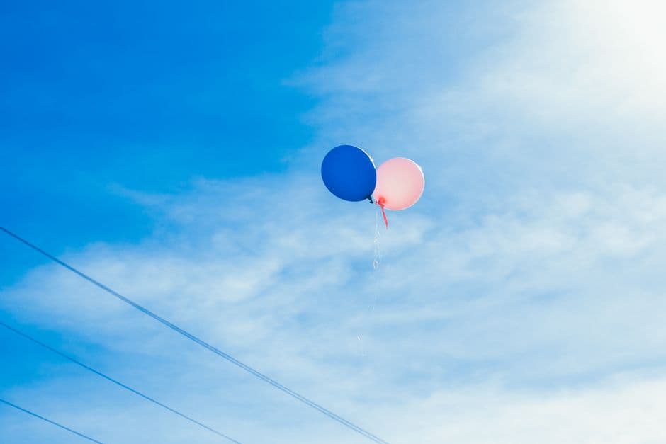 Two balloons floating in a clear blue sky, symbolizing freedom and joy.