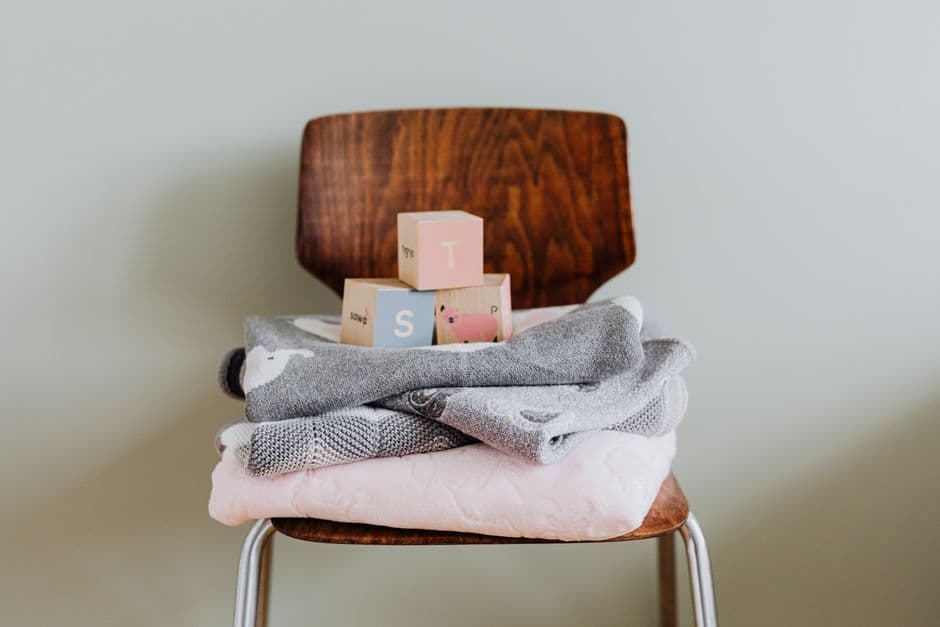 Wooden blocks and cozy baby blankets on a modern chair, ideal for nursery decor.