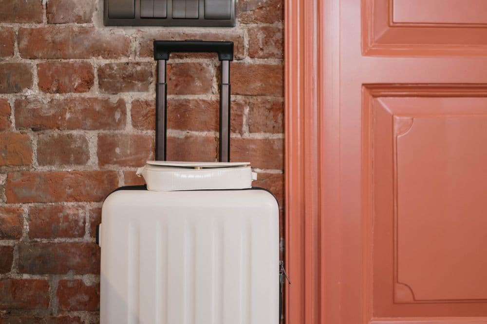 A packed suitcase standing ready beside a coral front door